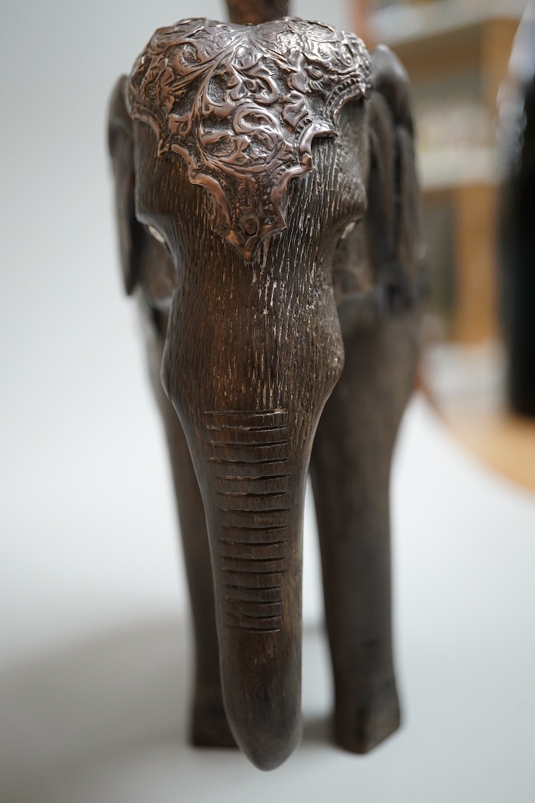 A late 19th century Indian white metal mounted carved hardwood model of an elephant, surmounted by a pair of removeable warthog tusks, overall height 40cm